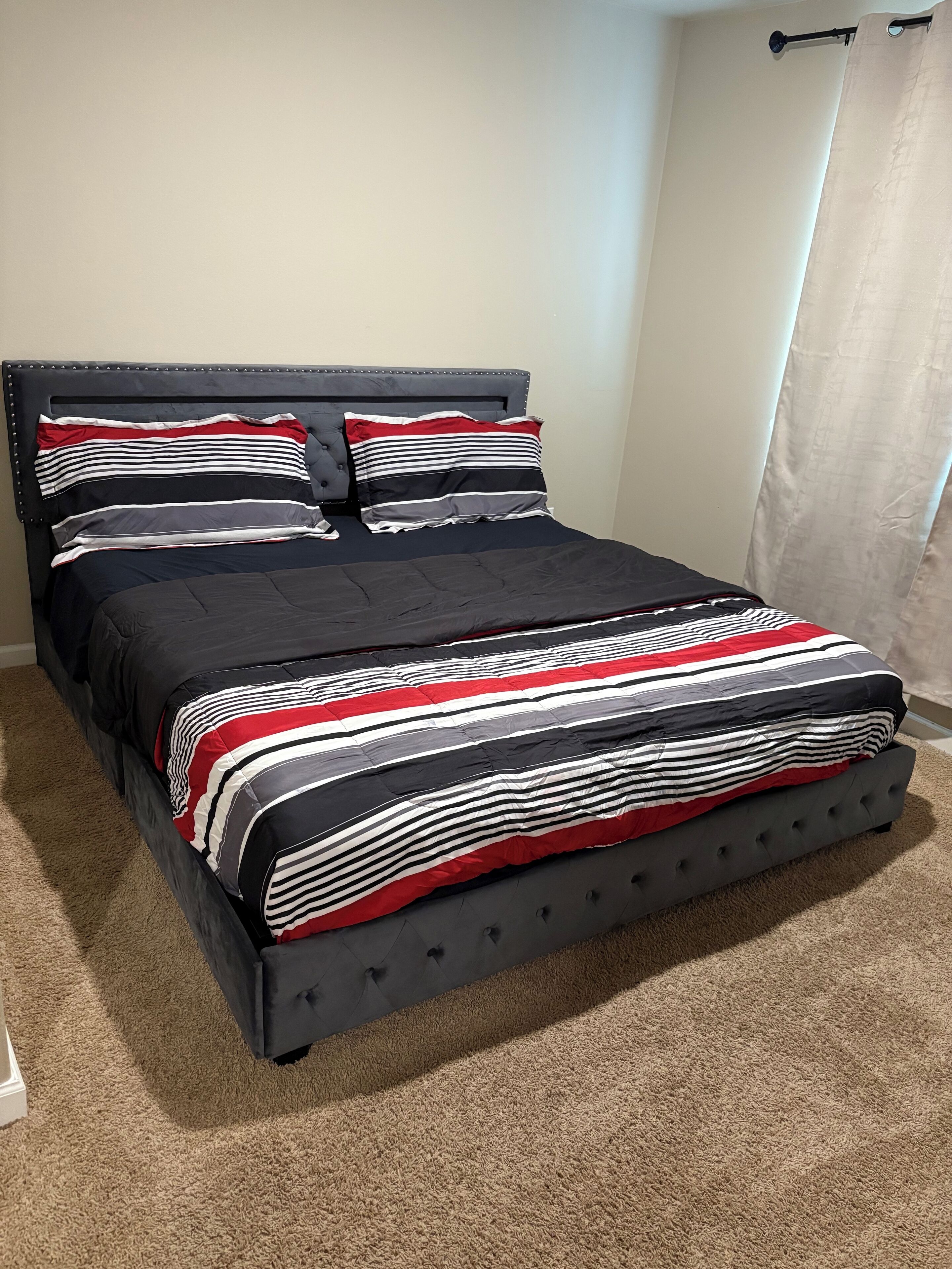 A bed with a dark headboard, multiple pillows, and a striped bedspread.