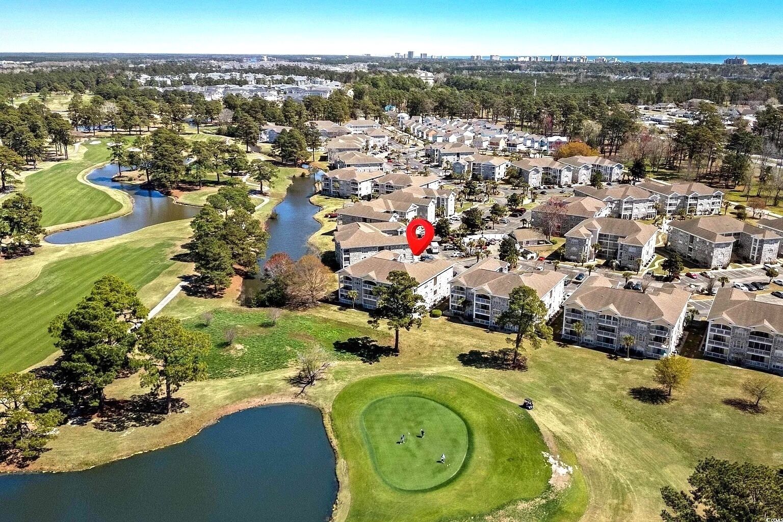 Ett flygbildsfoto av ett bostadsområde med en golfbana, en sjö och ett område med radhus.