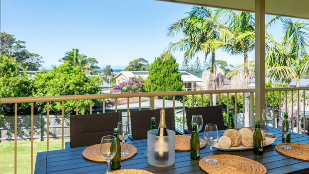 Mesa lista para comer con vista a palmeras y casas al fondo.