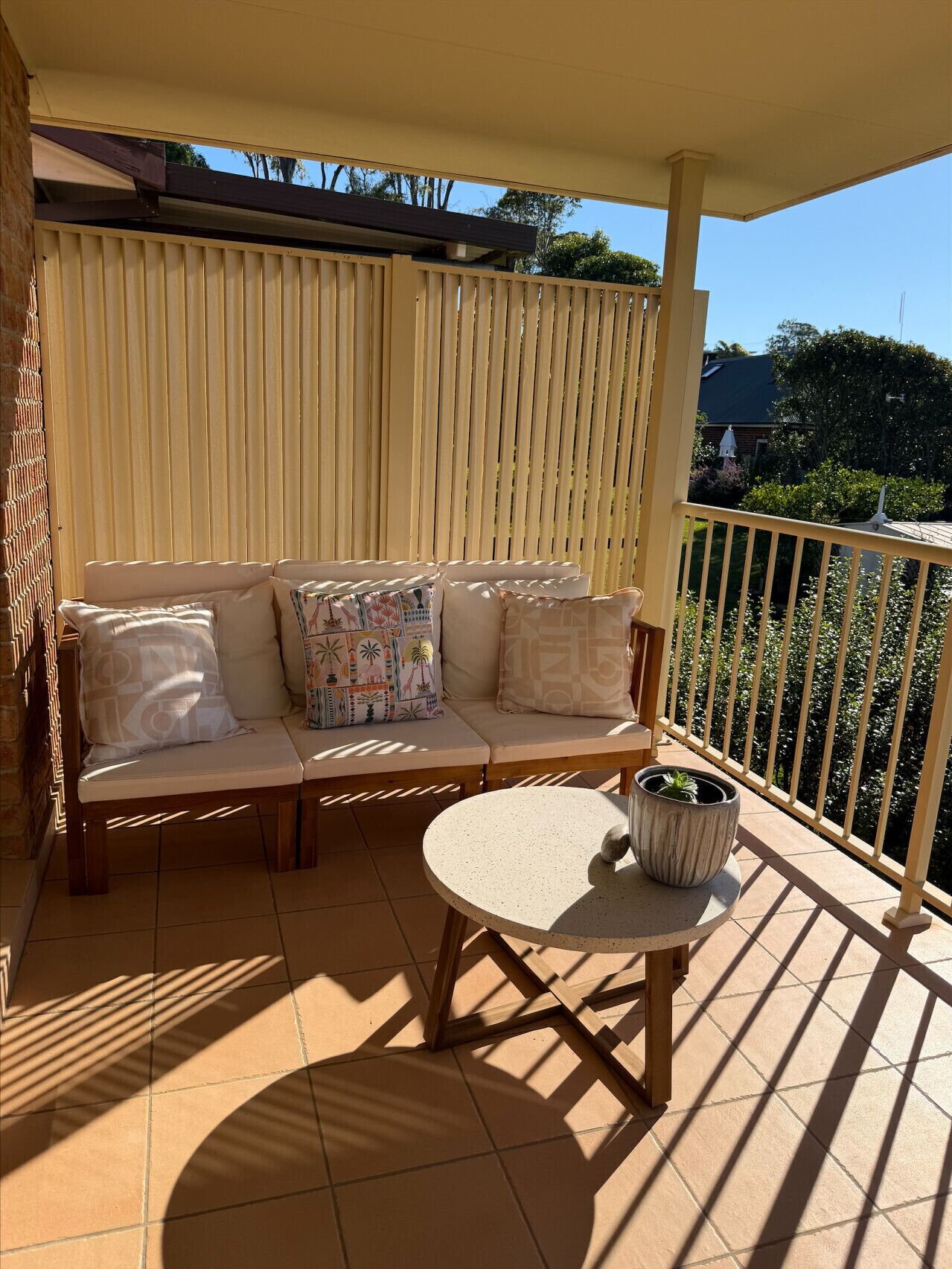 Ein Balkon mit einer Couch, einem kleinen Tisch und einem Blumentopf.