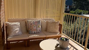 Ein Balkon mit einer Couch, einem kleinen Tisch und einem Blumentopf.