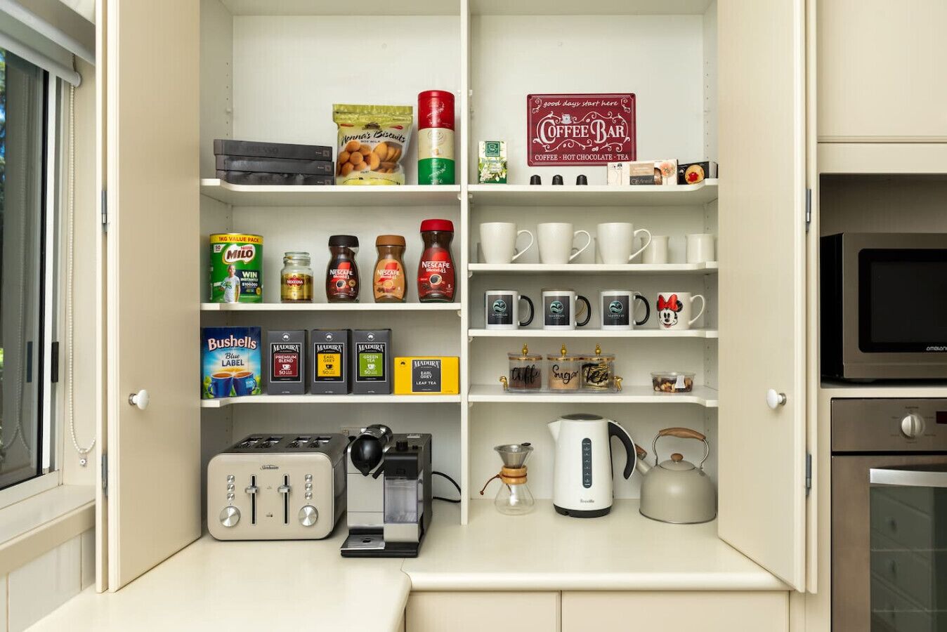 A kitchen with a coffee station, including a coffee machine, cups, and various coffee pods.