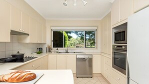 Una cocina moderna con un amplio ventanal, estufa, lavavajillas y refrigerador.