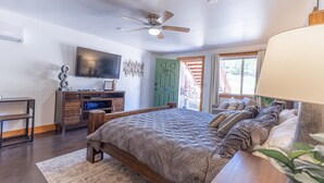 A bedroom with a bed, a TV, a ceiling fan, and a green door. - National Parks - Cozy stay and UFO Sightings (Alton)