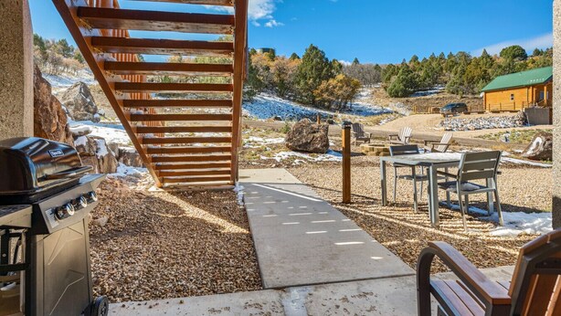 An outdoor patio with a grill, seating area, and a view of a cabin and trees. - National Parks - Cozy stay and UFO Sightings (Alton)
