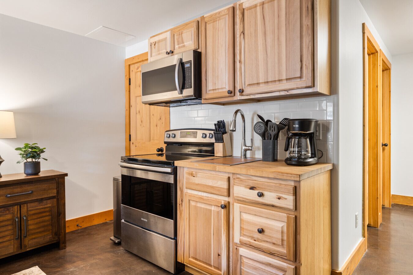 A kitchen with wooden cabinets, a stainless steel stove, a microwave, and a coffee maker.