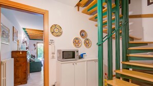 A staircase with green railings leading to a landing with a microwave and decorative plates. - The Green Emerald Family Retreat With Private Garden (Gignese)