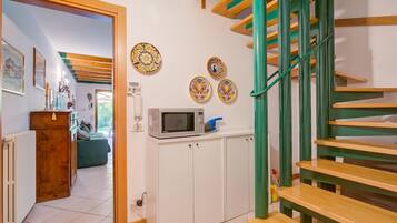 A staircase with green railings leading to a landing with a microwave and decorative plates.