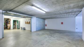 A spacious indoor area with a concrete floor and ceiling, a door leading to another room, and a fire extinguisher mounted on the wall.