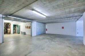 A spacious indoor area with a concrete floor and ceiling, a door leading to another room, and a fire extinguisher mounted on the wall. - The Green Emerald Family Retreat With Private Garden (Gignese)
