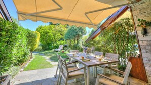 Eine Terrasse im Freien mit einem Essplatz, umgeben von Steinböden und Grünpflanzen.