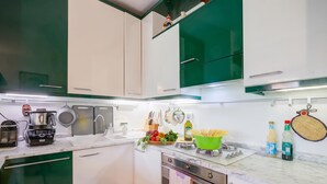 A modern kitchen with white and green cabinets, a built-in oven, and a variety of cooking utensils and appliances. - The Green Emerald Family Retreat With Private Garden (Gignese)