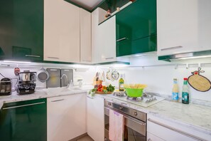 A modern kitchen with white and green cabinets, a built-in oven, and a variety of cooking utensils and appliances. - The Green Emerald Family Retreat With Private Garden (Gignese)