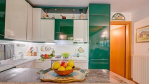 A kitchen with white and green cabinets, a fruit bowl on the counter, and a green refrigerator. - The Green Emerald Family Retreat With Private Garden (Gignese)