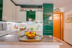 A kitchen with white and green cabinets, a fruit bowl on the counter, and a green refrigerator. - The Green Emerald Family Retreat With Private Garden (Gignese)