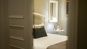 Een slaapkamer met een bed, een nachtkastje met een lamp en een spiegel aan de muur.