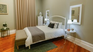A bedroom with a bed, bedside tables, a nightstand, a mirror, a potted plant, and a window with curtains. - GuestReady - Casa Conforto & Chiado - Room 5 (Ponta Delgada)