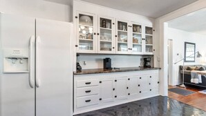Una cocina moderna con armarios blancos, un refrigerador empotrado y una cafetera sobre la encimera.