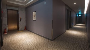 A hotel corridor with a marble floor, a framed artwork on the wall, and an elevator. - Lamer Hotel & Seawater Spa Busan (Busan)