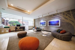 Um lobby moderno de hotel com áreas de estar, um balcão de recepção e obras de arte nas paredes.
