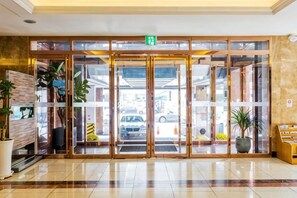 A hotel entrance with a glass door, a reception desk, and potted plants. - Lamer Hotel & Seawater Spa Busan (Busan)