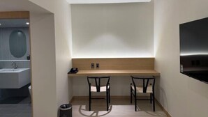 A modern bathroom with a large mirror, a sink, and a toilet. There is a wooden vanity with a mirror and a small table with two chairs. - Lamer Hotel & Seawater Spa Busan (Busan)
