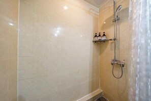 A shower area with a glass door, a handheld showerhead, and a shelf with toiletries. - Lamer Hotel & Seawater Spa Busan (Busan)