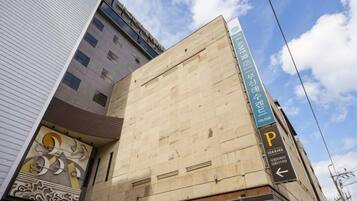 A building with a large, unfinished facade, a parking sign, and a clear sky.
