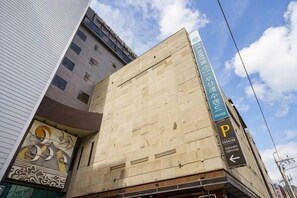 A building with a large, unfinished facade, a parking sign, and a clear sky. - Lamer Hotel & Seawater Spa Busan (Busan)