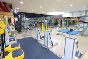 Un gimnasio con equipos de ejercicio variados, incluyendo máquinas de pesas y pesas libres.