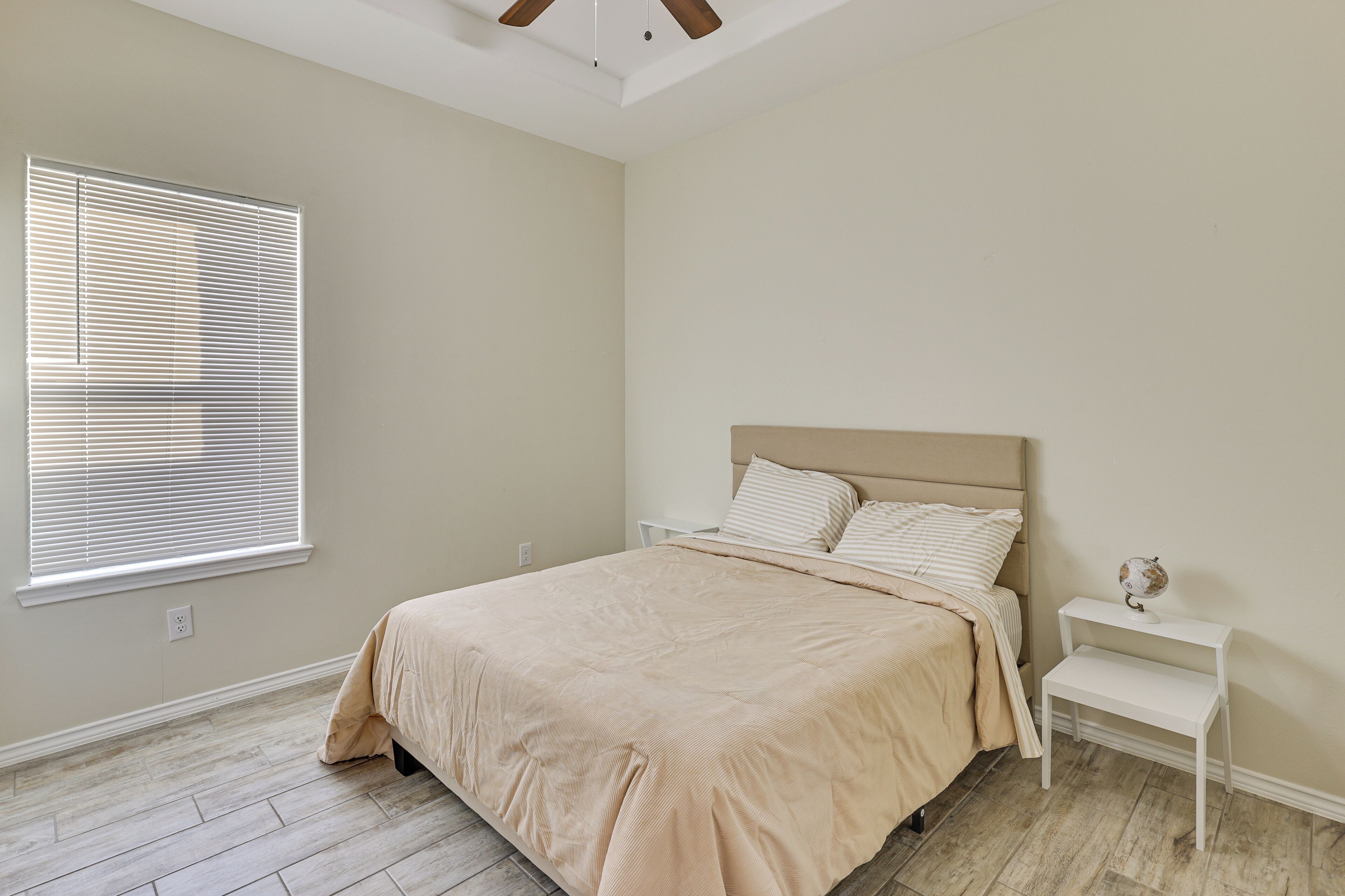 A bedroom with a bed, nightstand, and a globe on the nightstand.