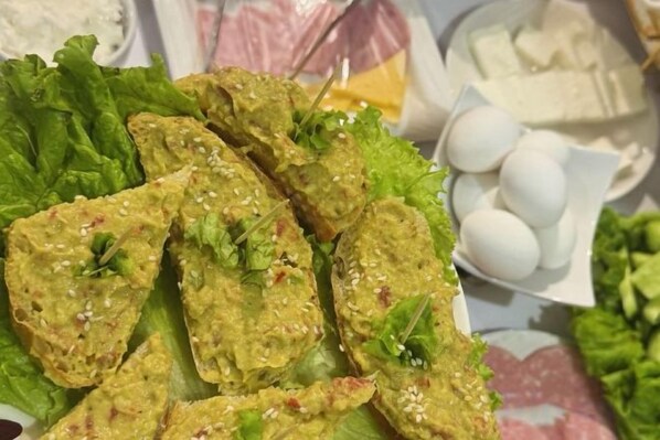 A plate of food with a variety of items including a green leafy vegetable, a white dish with eggs, and a white container with a yellowish substance. - Sands of Time Apart Hotel (Baku)