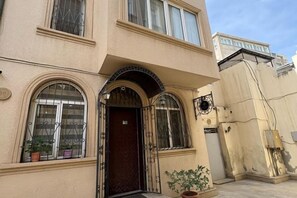 A building with a dark entrance door, arched windows, and potted plants. - Sands of Time Apart Hotel (Baku)