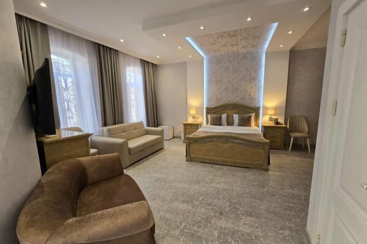 A modern hotel room with a large bed, a sofa, a TV, and a desk.