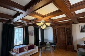 A room with a wooden ceiling, a piano, a sofa, and a chandelier. - Sands of Time Apart Hotel (Baku)