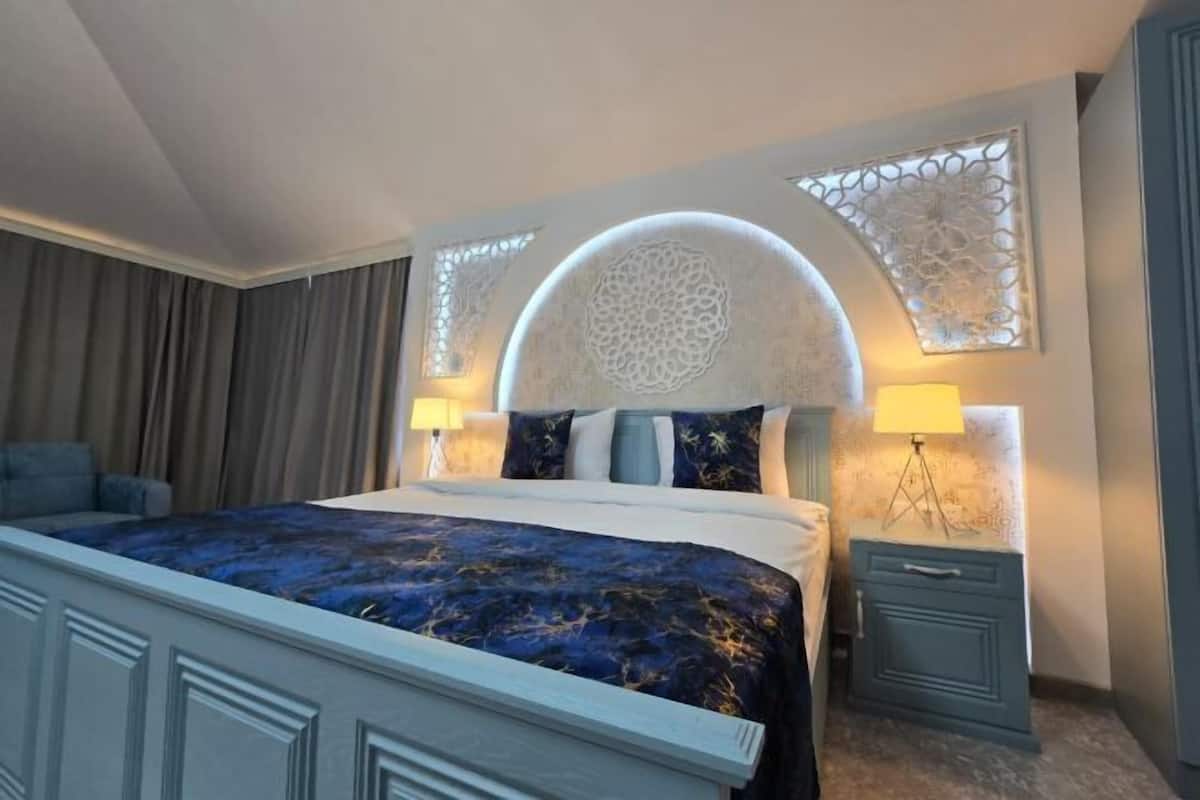 A modern hotel room with a large bed, two bedside tables, and a decorative wall with a circular pattern.