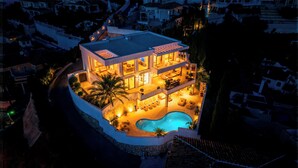 A multi-story house with a swimming pool, outdoor seating, and a well-lit interior. - VILLA RIVIERA THE VIEW (Mijas)