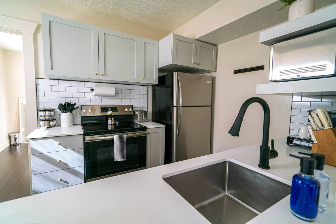 A modern kitchen with white cabinets, stainless steel appliances, and a black faucet.