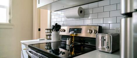 Una cocina moderna con electrodomésticos de acero inoxidable, armarios blancos y salpicadero de azulejos.