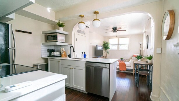 A modern kitchen with a central island, stainless steel appliances, and a dining area with a ceiling fan. - Relaxing & Central SLC Apt near Trolley Square (Salt Lake City)