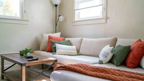 A cozy living room with a sofa, a coffee table, and a floor lamp. - Relaxing & Central SLC Apt near Trolley Square (Salt Lake City)