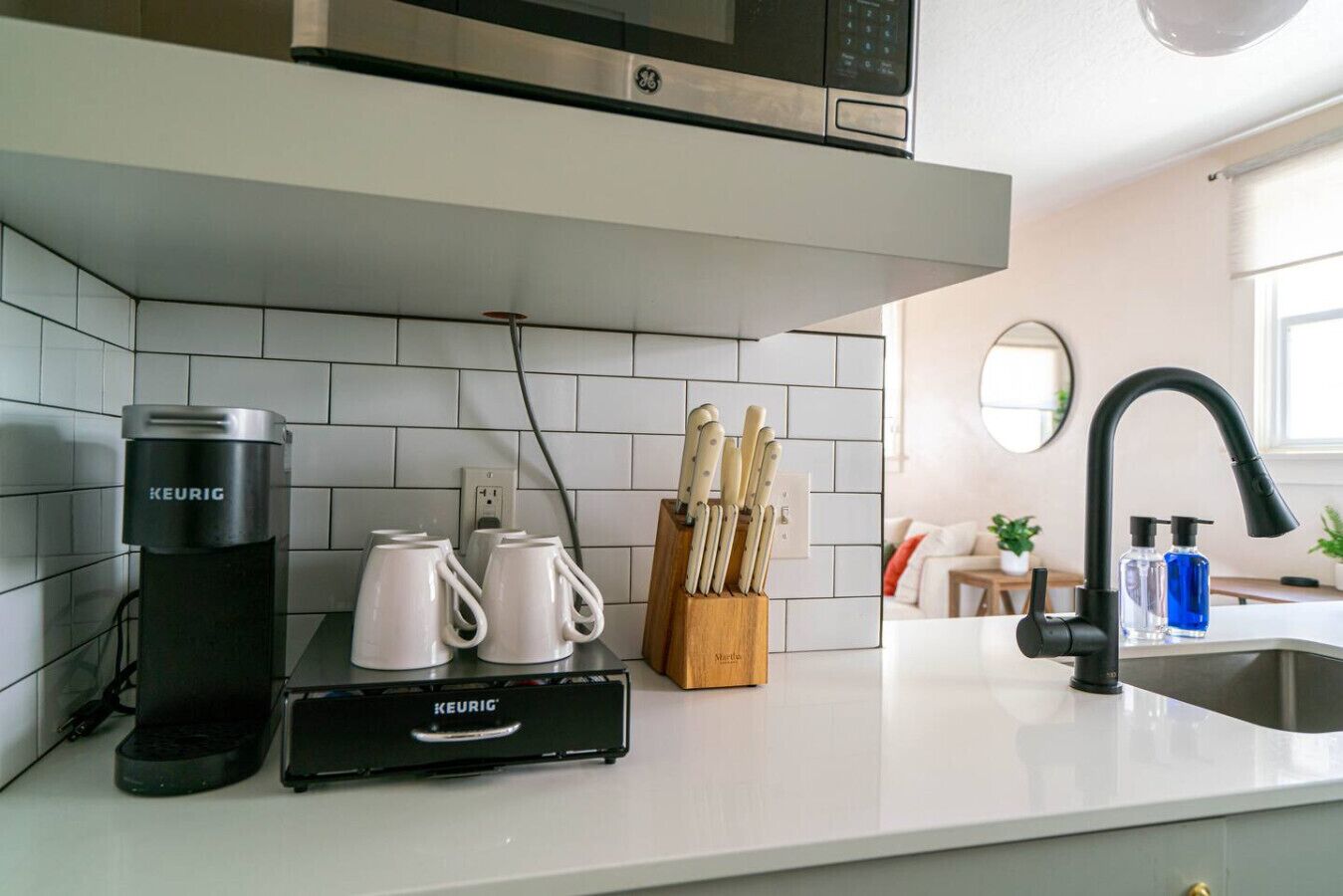 Eine Küche mit Kaffeemaschine, Tassen, einem Messerblock und einer Mikrowelle.