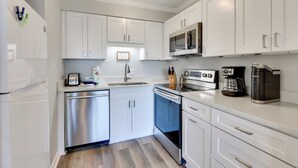 Een moderne keuken met witte kastjes, roestvrijstalen apparatuur en een inbouwmagnetron.