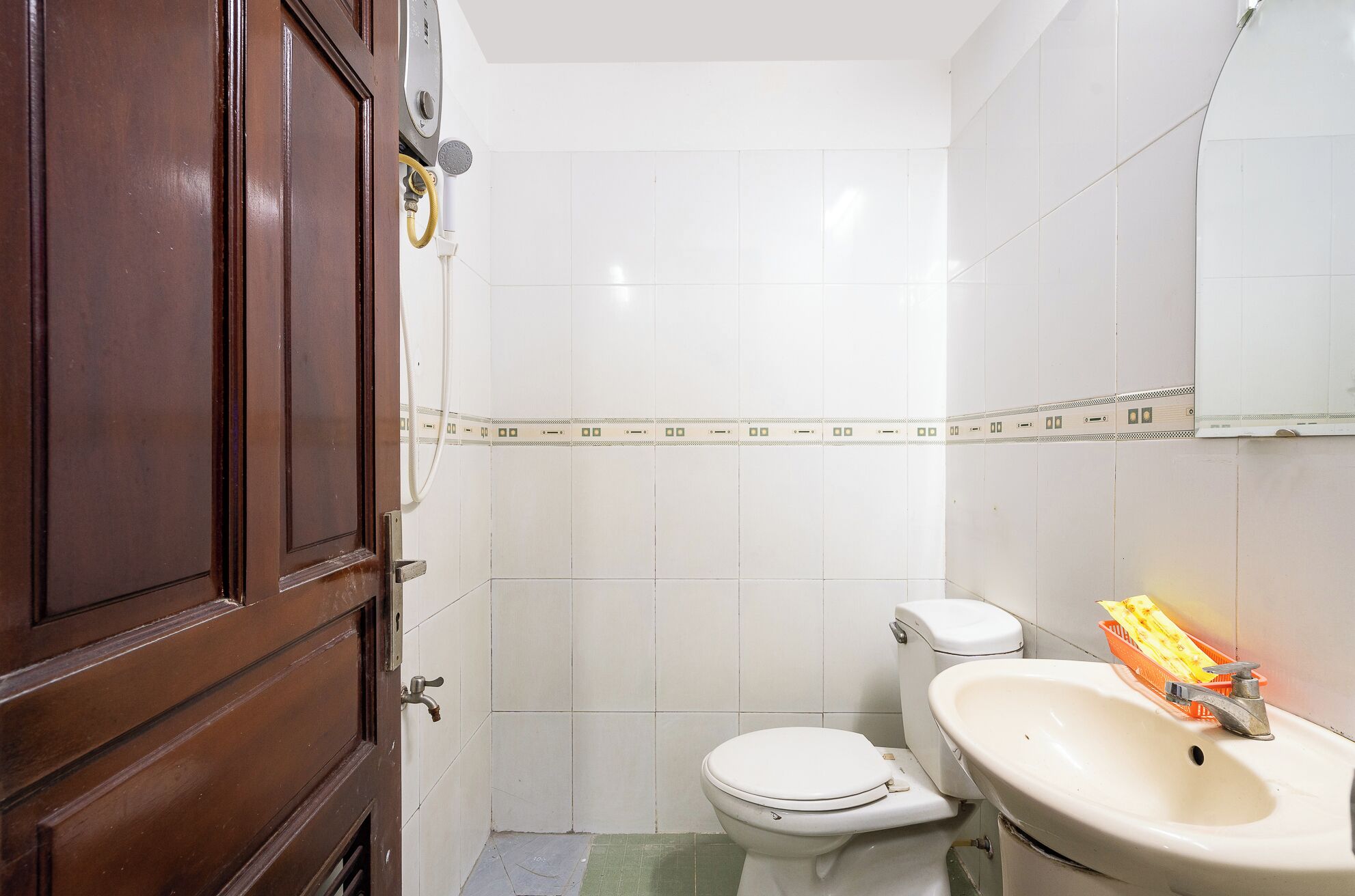 A small bathroom with a toilet, sink, and a wooden door.