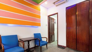 A reception area with two blue chairs, a small wooden table, and a wooden wardrobe. - Collection O District Tan Phu - Tien Thang Hotel  (Ho Chi Minh City)