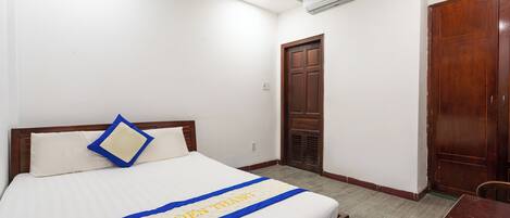 Una habitación de hotel con una cama, una puerta de madera y una mesita.