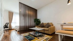 A modern living room with a sofa, coffee table, and a dining area with a bench. - Lancaster Ho Chi Minh Serviced Apartment Official (Ho Chi Minh City)