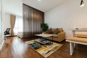 A modern living room with a sofa, coffee table, and a dining area with a bench. - Lancaster Ho Chi Minh Serviced Apartment Official (Ho Chi Minh City)