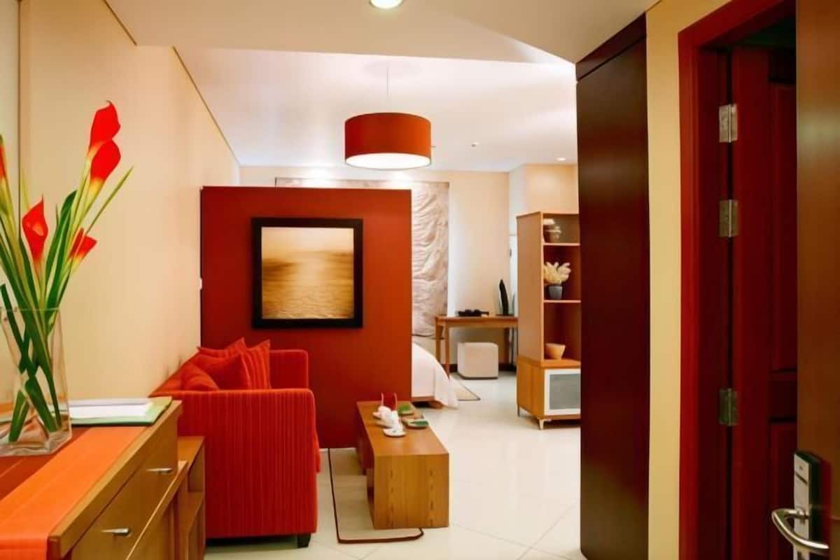 Un salon moderne avec un canapé rouge, une table basse en bois et un tableau accroché au mur.