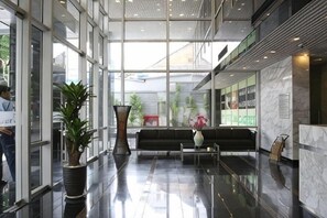 A modern lobby with glass walls, a seating area, and potted plants. - Lancaster Ho Chi Minh Serviced Apartment Official (Ho Chi Minh City)
